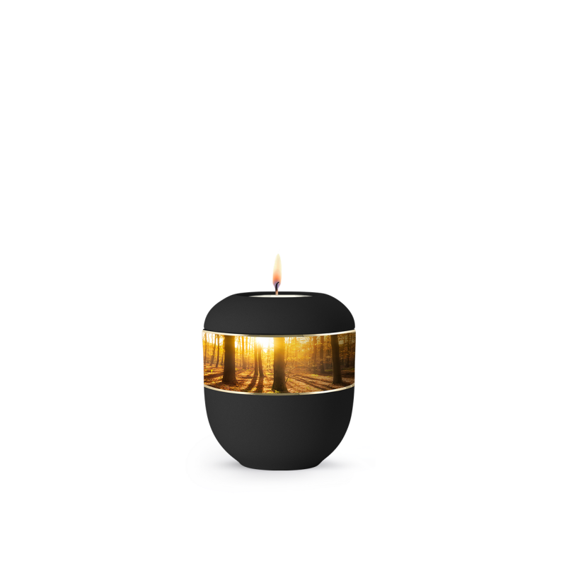 Die schwarze Urne aus Samton mit umlaufendem Zierband zeigt eine Waldlandschaft und hat eine runde Form, mit einer Flamme, die oben sichtbar ist.