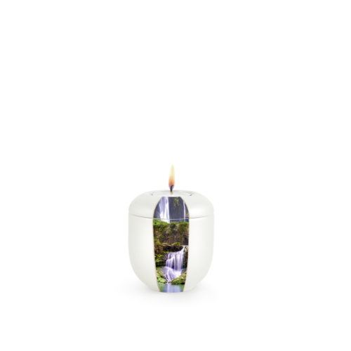 Gedenklicht aus Perlmutt mit Wasserfall-Motiv, rundliche Form, helle Farbe, Gesamtansicht mit brennender Flamme auf der Oberseite.