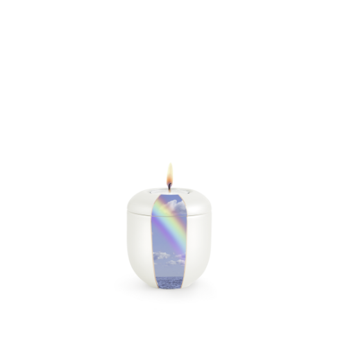 Ein rundes, perlmuttfarbenes Gedenklicht mit einem Regenbogenmotiv auf der Vorderseite und einer flammenden Dochtspitze in der Mitte.