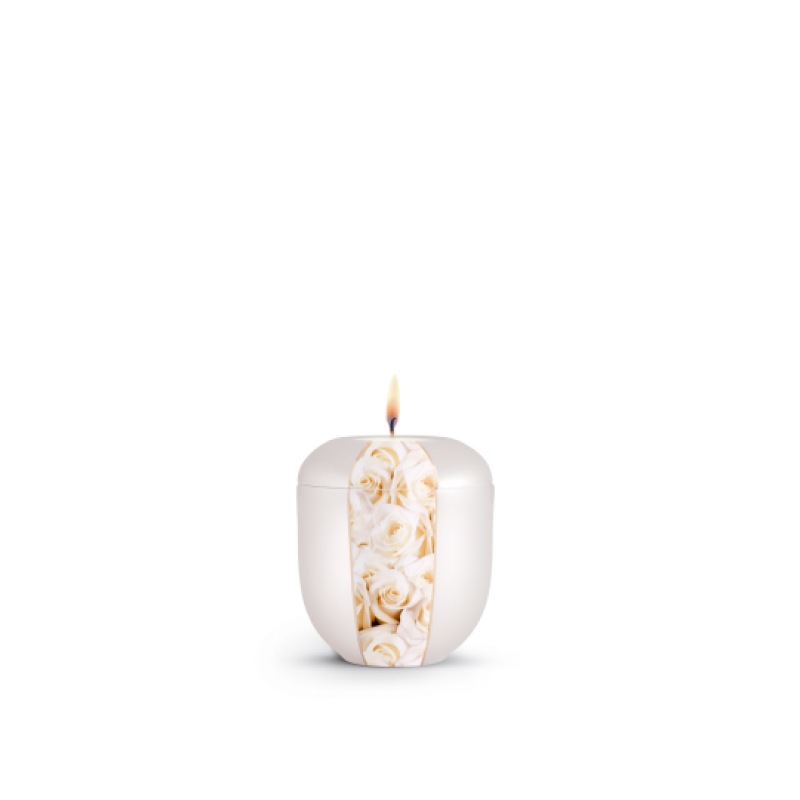 Ein Gedenklicht in Perlmuttfarbe mit einem dekorativen Streifen aus weißen Rosen, ovaler Form und brennender Flamme, Gesamtansicht.