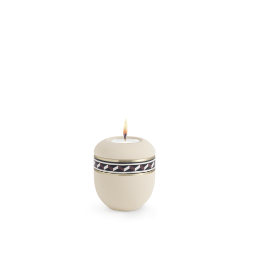 Gedenklicht in Creme, handbemalt mit zackenförmigem Muster in Schwarz und Weiß, runde Form, Gesamtansicht mit brennender Kerze.