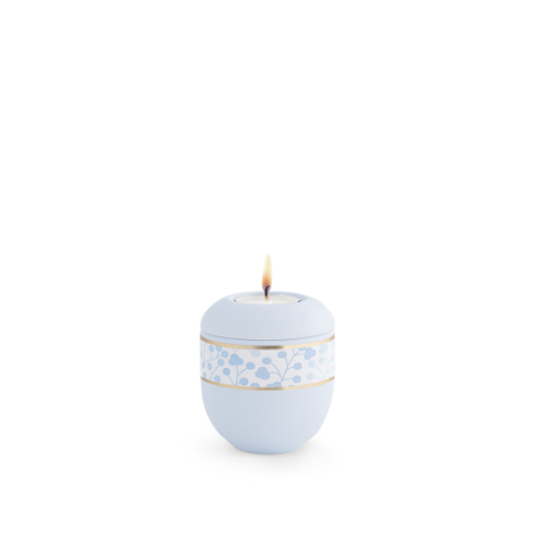 Gedenklicht in Hellblau mit Soft-Touch-Oberfläche, verziert mit Blätterdekor und goldenen Streifen, in runder Form und mit brennender Flamme oben.