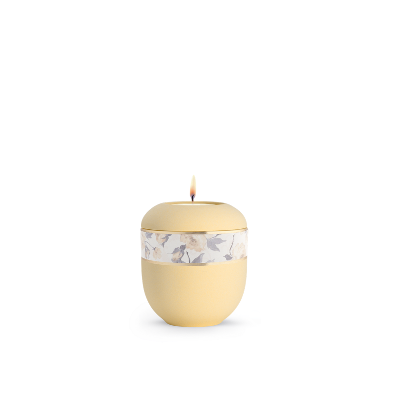 Gedenklicht in Gelborange mit Soft-Touch-Oberfläche und Blumendekor, rundliche Form, Gesamtansicht mit brennender Kerze oben.