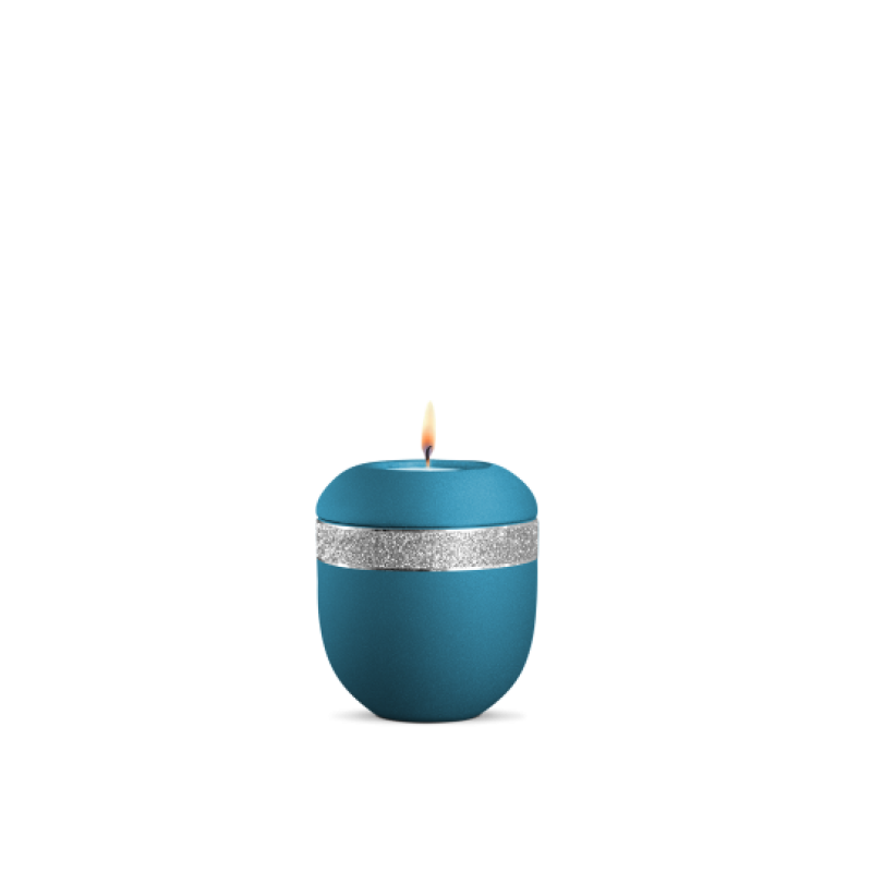 Ein gedenklicht in velvet Arctic Türkis mit glitzerndem silbernen Dekor und einer brennenden Kerze, in runder Form und Gesamtansicht.