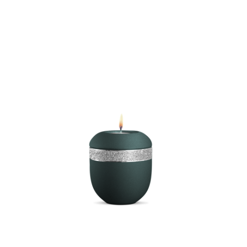 Ein Gedenklicht in velvet Petrol mit glitzerndem silbernem Dekor, runde Form und eine brennende Kerze auf der Oberseite, Gesamtansicht.