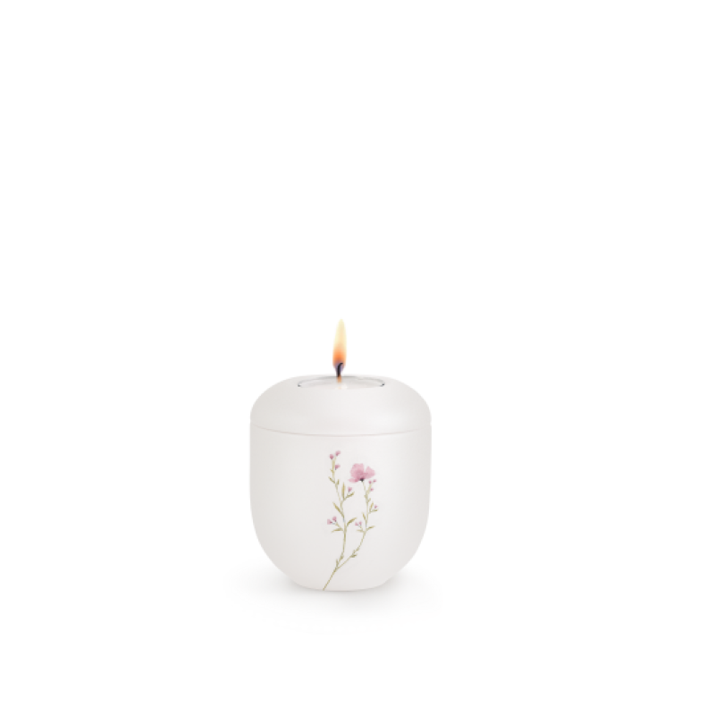 Gedenklicht in Perlmutt-Mattweiß aus Porzellan mit einer rosa Blumenwiese als Dekor, in runder Form und mit brennender Flamme, Gesamtansicht.