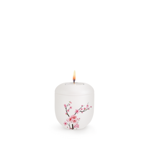 Gedenklicht in Perlmutt-Mattweiß aus Porzellan mit Kirschblüten-Motiv, runde Form, Gesamtansicht mit brennender Kerze oben.