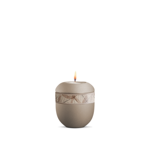 Gedenklicht in velvet Champagner mit dekorativer Banderole aus Grasfasern und Blättern, runde Form, Gesamtansicht mit brennender Flamme.