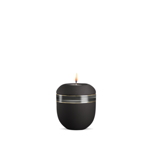 Ein schwarzes Gedenklicht aus Velvet mit einer runden Form, verziert mit einem silbernen Wellendekor, in Gesamtansicht mit brennender Flamme.