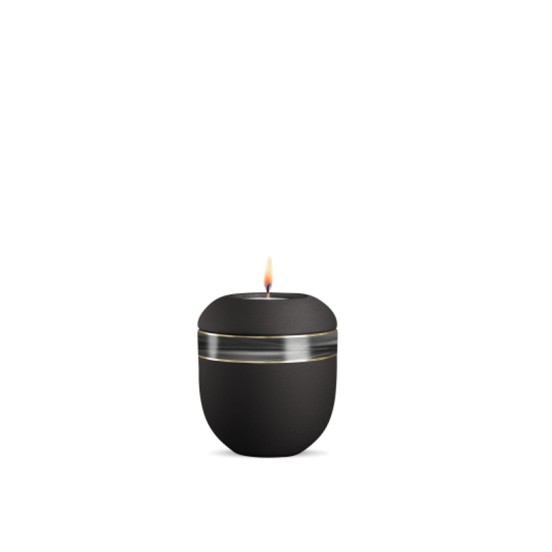 Ein schwarzes Gedenklicht aus Velvet mit einer runden Form, verziert mit einem silbernen Wellendekor, in Gesamtansicht mit brennender Flamme.
