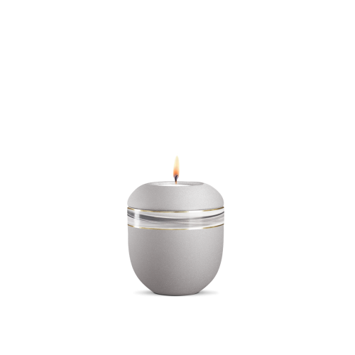 Ein silbergraues Gedenklicht mit Wellendekor, aus mattem Material, in runder Form, mit einer flammenden Kerze auf der Oberseite, Gesamtansicht.