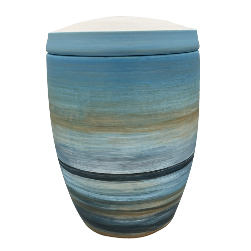 Die Urne "Horizont" ist aus Keramik, hat eine ovale Form und zeigt eine mehrfarbige, sanfte Farbverlaufsgestaltung in Blau- und Erdtönen mit einem abgerundeten Deckel.