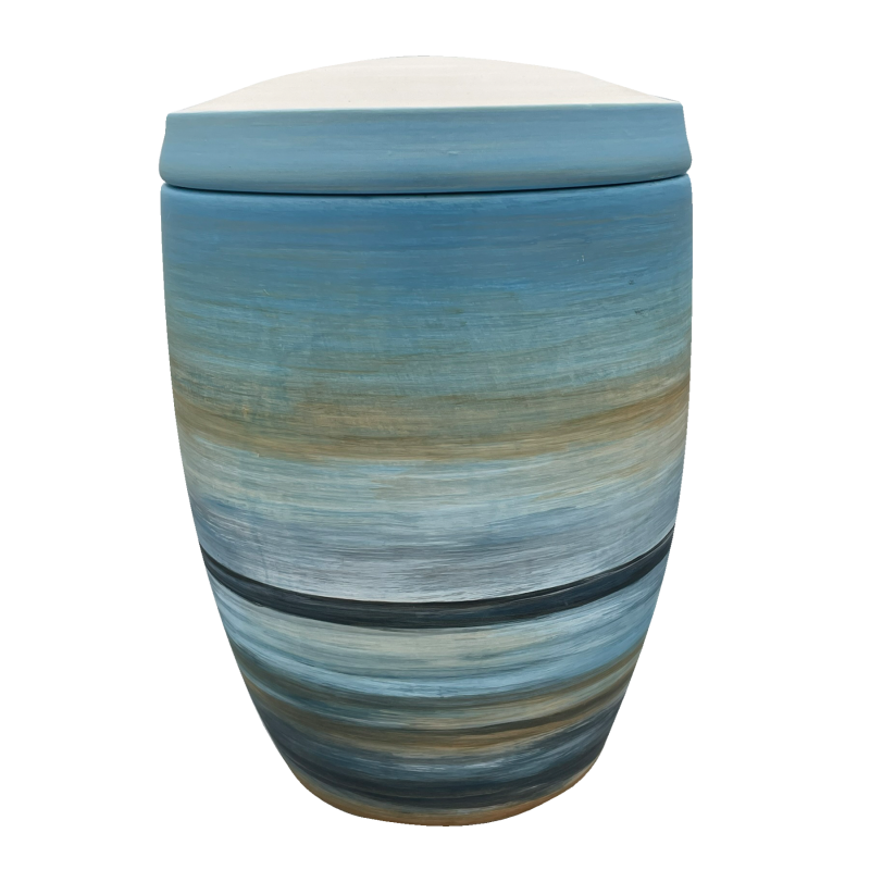 Die Urne "Horizont" ist aus Keramik, hat eine ovale Form und zeigt eine mehrfarbige, sanfte Farbverlaufsgestaltung in Blau- und Erdtönen mit einem abgerundeten Deckel.