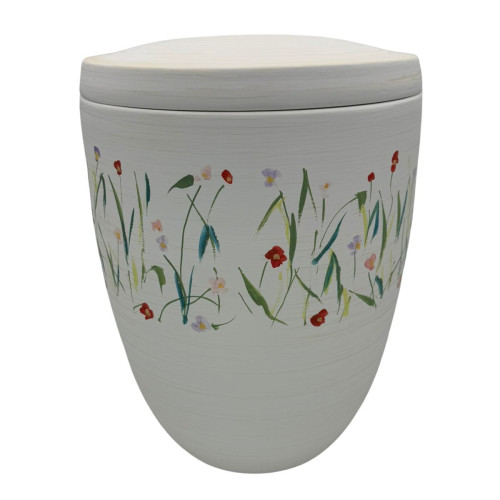 Die Alto Urne "Blütentanz" ist oval geformt, in Weiß gehalten und mit bunten Blumenmotiven verziert, die den gesamten Umfang schmücken.