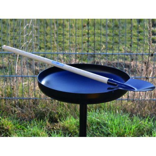 Pastorenschaufel mit langem Holzstiel, schwarzer Schaufelkopf aus Metall, Gesamtansicht auf einem runden, schwarzen Behälter im Freien.