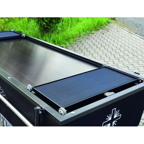 Ein Rollschlitten aus Metall mit schwarzer, rutschfester Oberfläche und seitlichen Rollen, abgebildet in einer Detailansicht auf einem Sargwagen.
