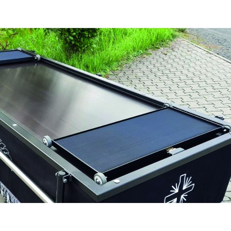 Ein Rollschlitten aus Metall mit schwarzer, rutschfester Oberfläche und seitlichen Rollen, abgebildet in einer Detailansicht auf einem Sargwagen.