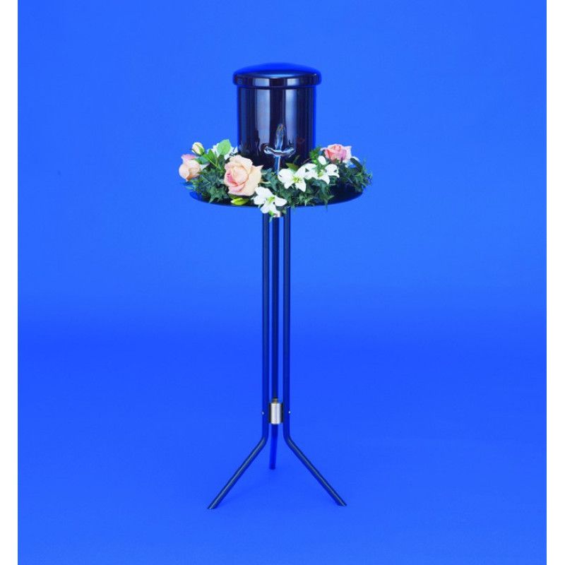 Der Urnentisch Raffael ist schwarz, hat eine runde Ablagefläche mit Blumenarrangement und steht auf einem stabilen, dreibeinigen Gestell.