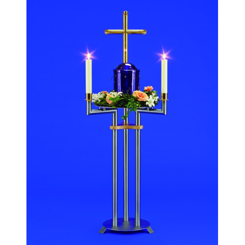 Urnenkandelaber Medea aus Metall in Silber und Gold mit einem blauen Urnenbehälter, zwei Kerzenhaltern und einem Messingkreuz, Gesamtansicht mit Blumenarrangement.