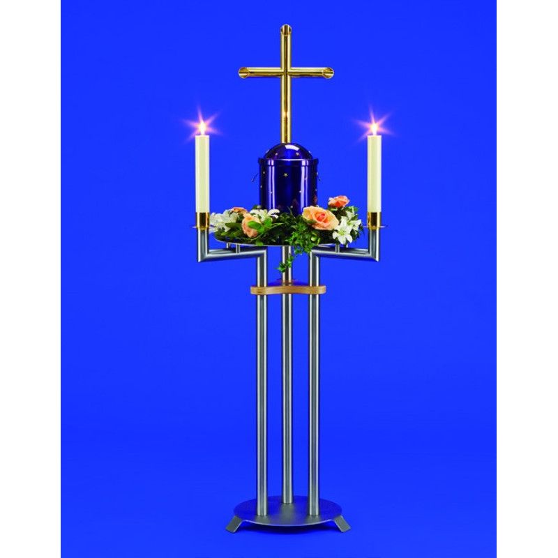 Urnenkandelaber Medea aus Metall in Silber und Gold mit einem blauen Urnenbehälter, zwei Kerzenhaltern und einem Messingkreuz, Gesamtansicht mit Blumenarrangement.