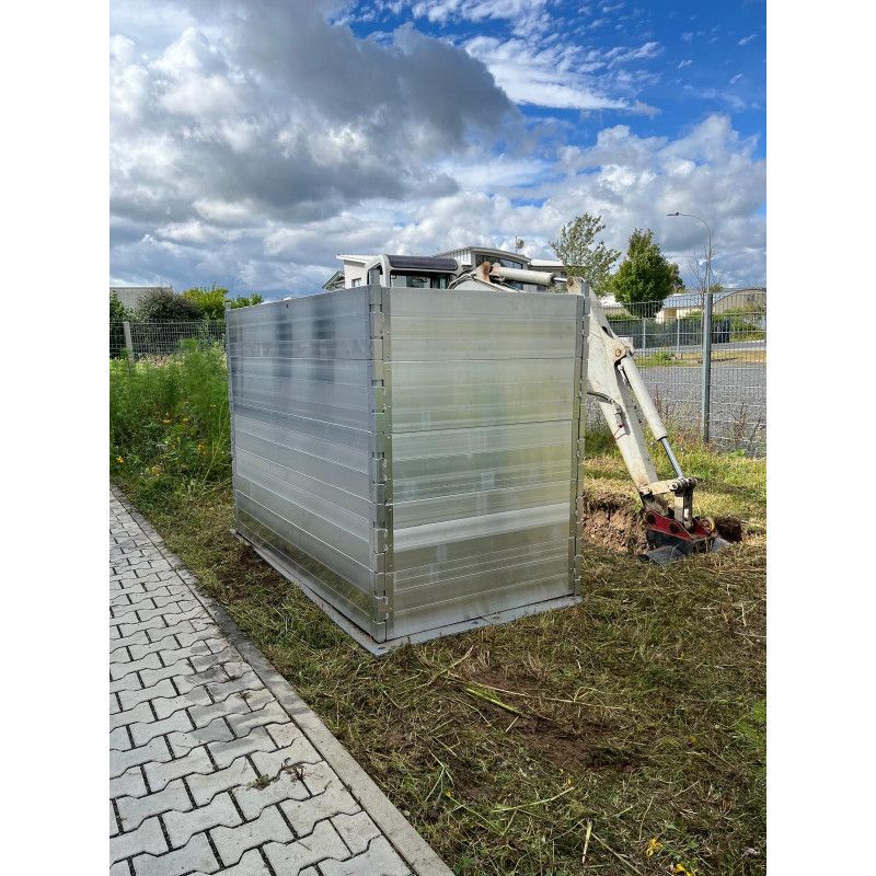 Der Stapelring aus Aluminium-Bordwandprofilen ist in einer silbernen, rechteckigen Form zu sehen, zerlegbar und steht auf einem unbefestigten Untergrund.