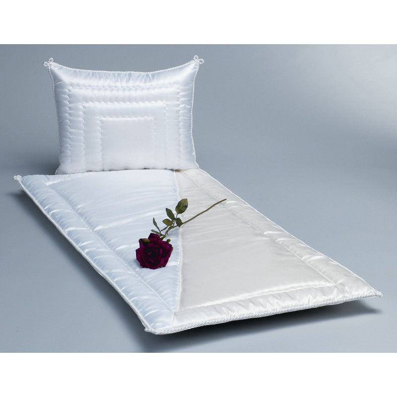 Eine cremefarbene Glanzseide mit einer weißen Serge-Oberfläche, bestehend aus einer Decke und einem Kissen, auf dem eine rote Rose liegt.
