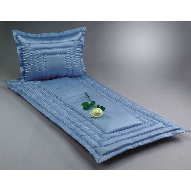 Eine hellblaue Glanzseide mit einem gesteppten Muster, bestehend aus einer Liegefläche und einem Kopfkissen, dekoriert mit einer weißen Rose.