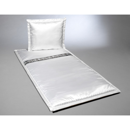 Deckengarnitur aus weißem Serge mit einem Zierband in Schwarz und Silber, bestehend aus einer Decke und einem Kissen in Gesamtansicht.