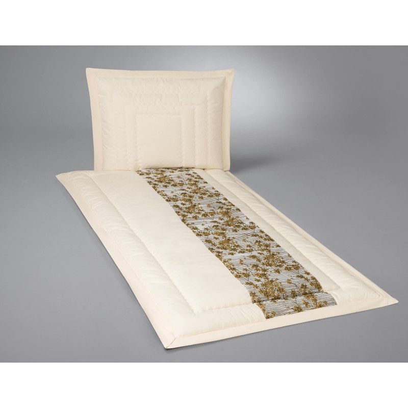 Deckengarnitur aus naturfarbenem Rohgewebe mit einem cremefarbenen Bezug und einem Blumeneinsatz in Gold, bestehend aus Decke und Kopfkissen in Gesamtansicht.