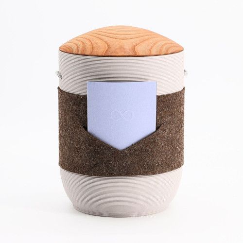 Urne Mira Band in Braun-Blau Grau aus Tonerde mit einem runden, grauen Körper, einem braunen Filzband und einem Holzdeckel in hellem Holzton.