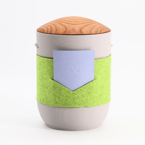 Urne Mira Band in Grün-Blau-Grau aus Tonerde mit einem grauen Körper, einem Holzdeckel und einem grünen Filzband sowie einer blauen Applikation.