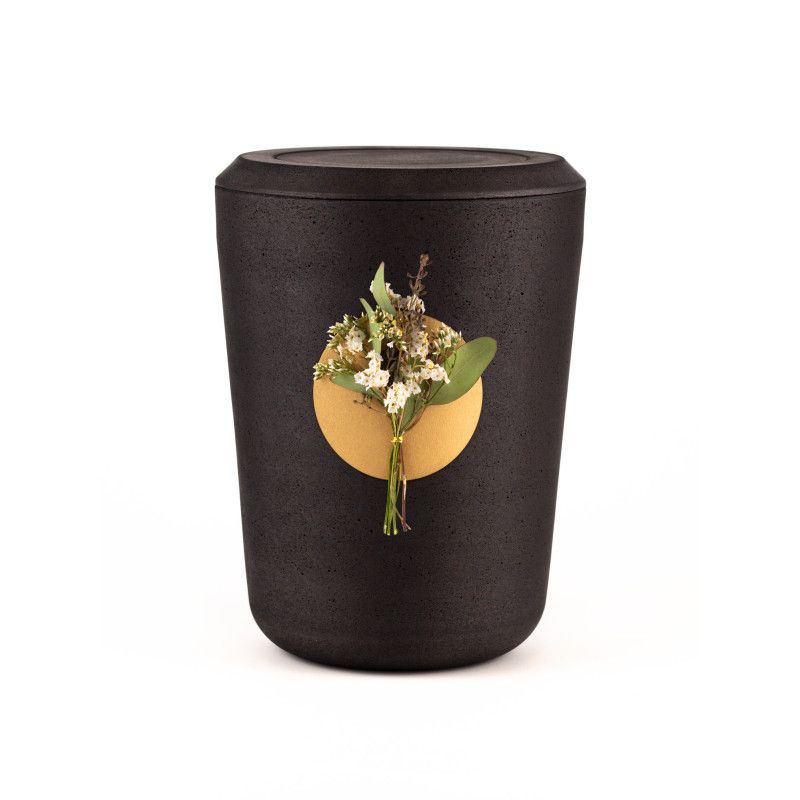 Die Kohleurne Eukalyptus ist schwarz, zylindrisch geformt und hat eine runde, goldfarbene Fläche mit einer Blumenarrangement-Dekoration.