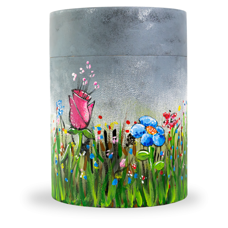 Die Bambusurne in zylindrischer Form zeigt ein handgemaltes Blumenwiesenmotiv mit einer rosa Rose und blauen Blumen auf grauem Hintergrund.