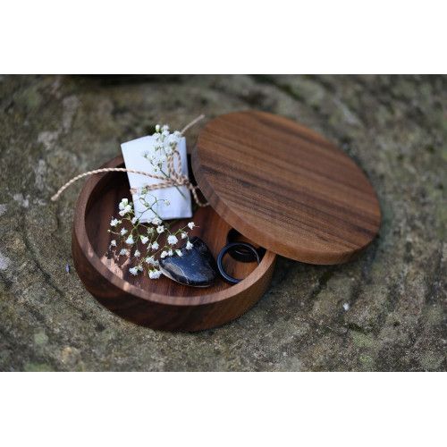 Die Bijou-Schatulle aus Holz hat eine runde Form, einen Deckel und enthält kleine Gegenstände wie einen Stein, Ringe und Blumen, in einer Gesamtansicht.