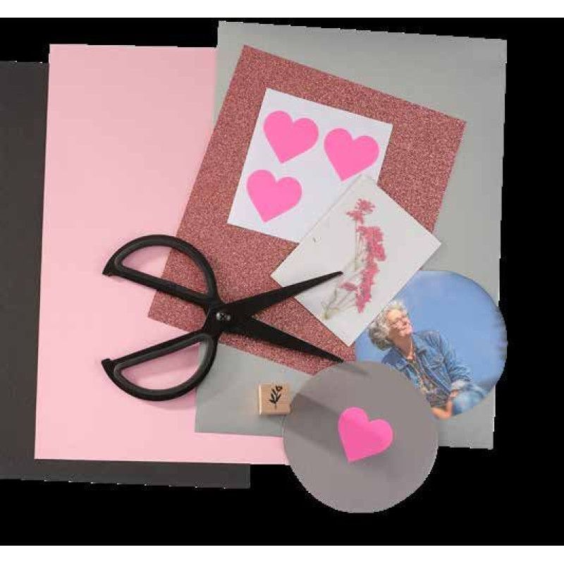 Auf dem Foto sind verschiedene Bastelmaterialien wie farbige Papiere in Rosa, Grau und Schwarz, eine Schere, Aufkleber in Herzform und ein Bild zu sehen.